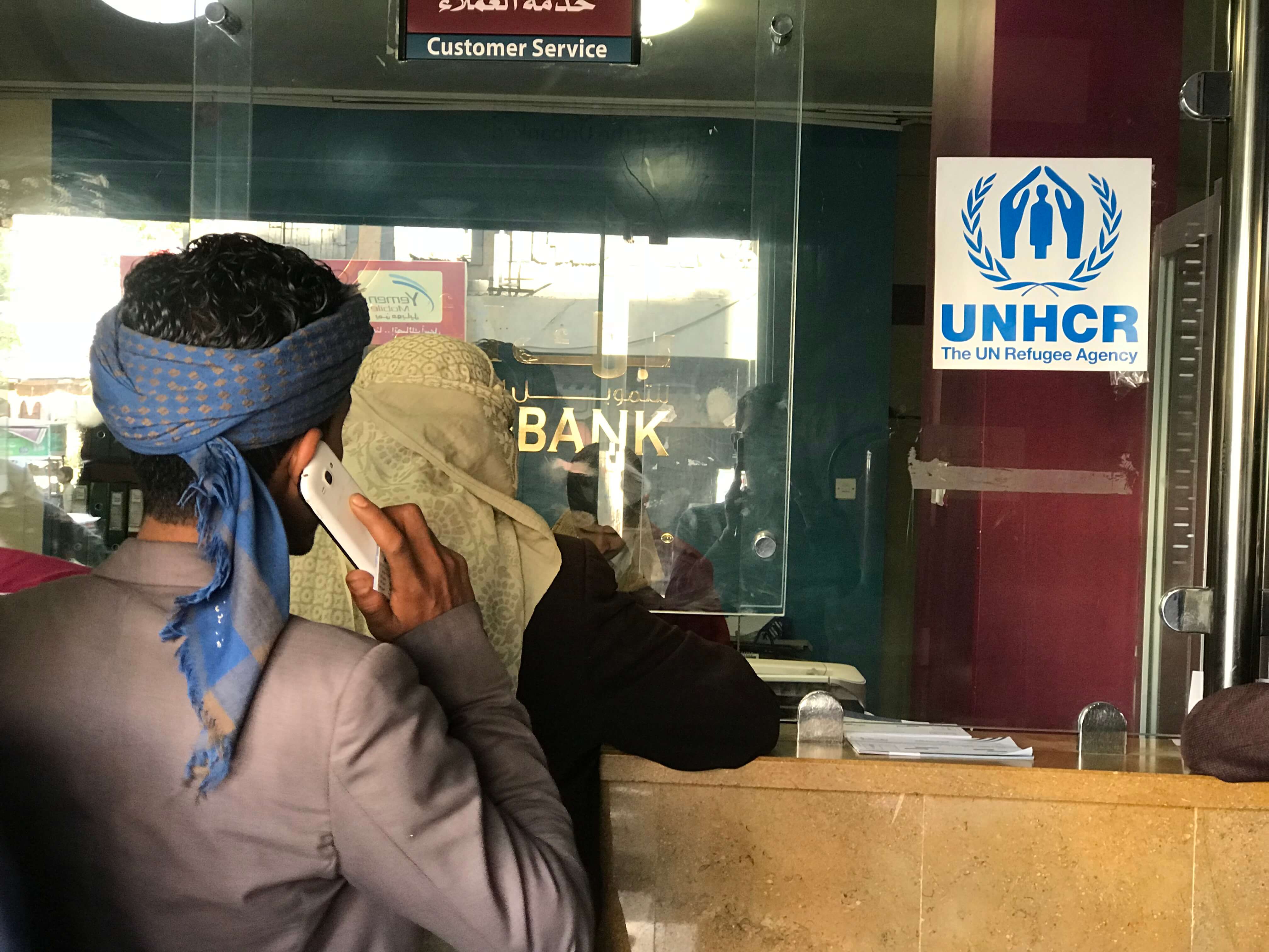 Displaced Yemenis wait in line to receive a UNHCR cash rental subsidy at Al Amal Bank in Sana’a Yemen.