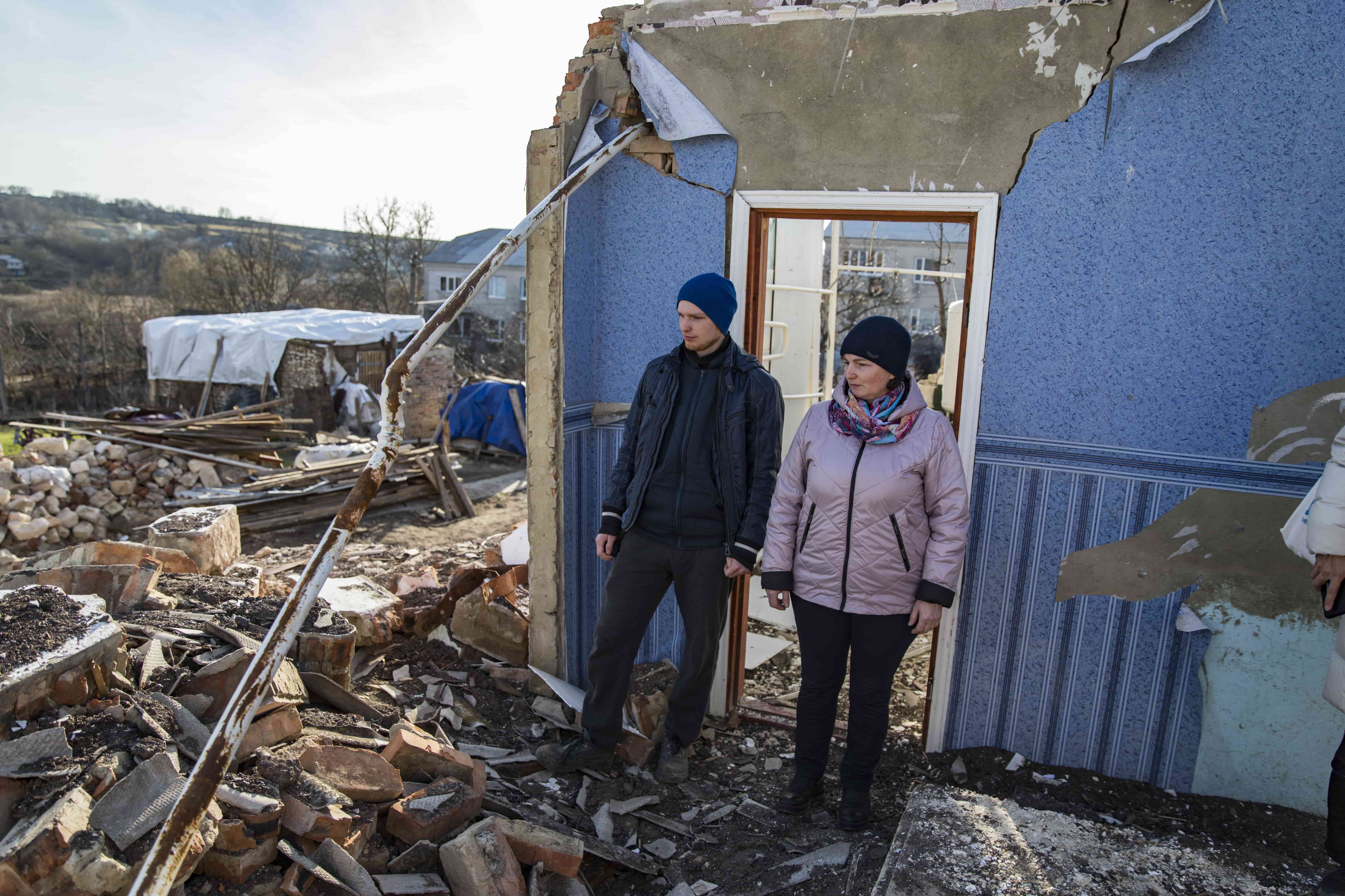 Vitali and his mother Halyna stand in the ruins of a family home following a missile attack on their village, Ukraine