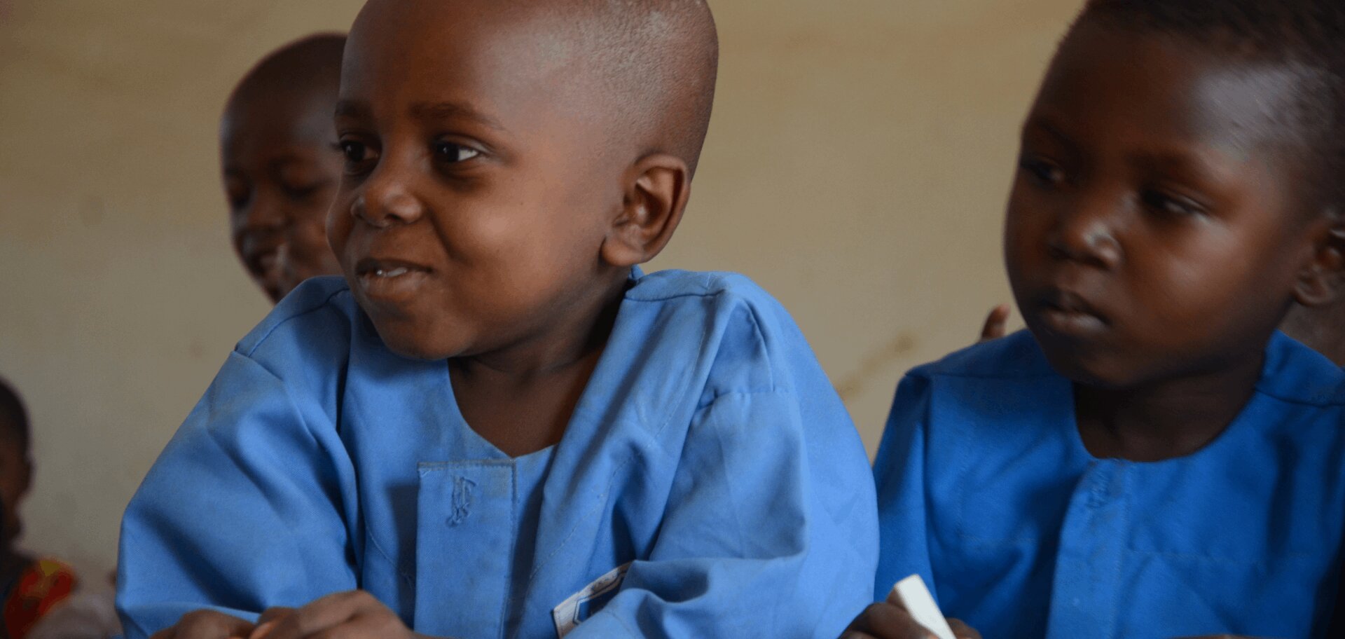 Azaiya, a six-year-old boy from Cameroon, sits with classmates during a lesson