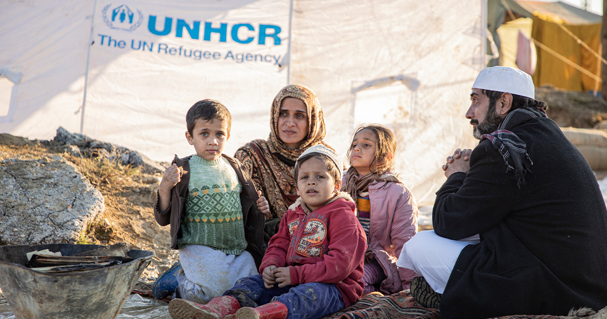 Family sits in front of UNHCR tent © UNHCR