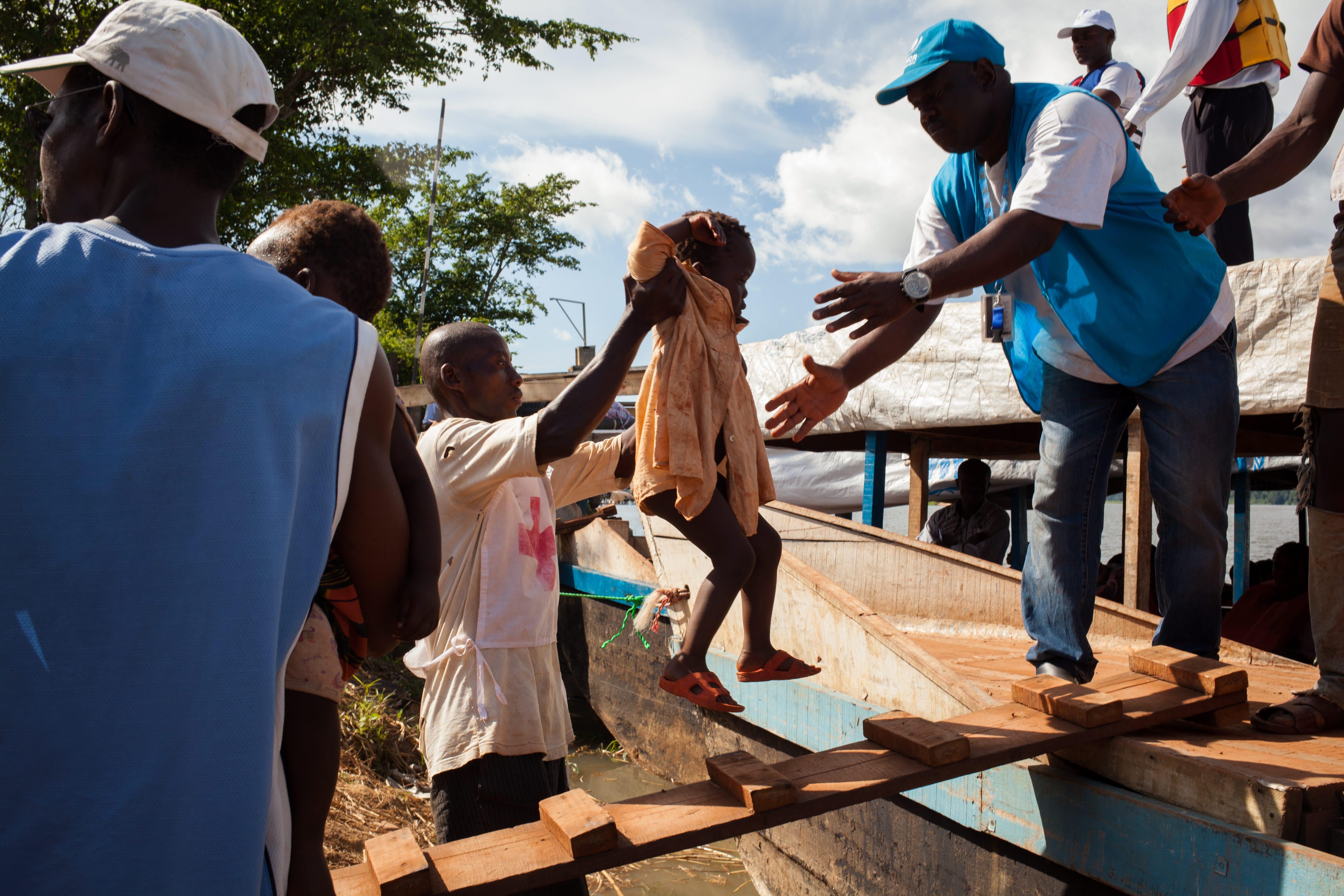 UNHCR staff helping a Congolese refugee girl to go on a boat that will get her and her family back to DRC.