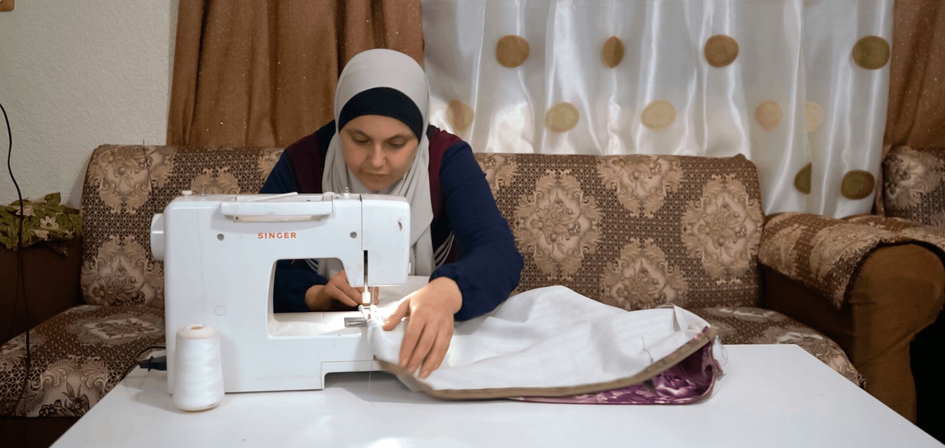 Zuzan works at her sewing machine at her home in Jordan