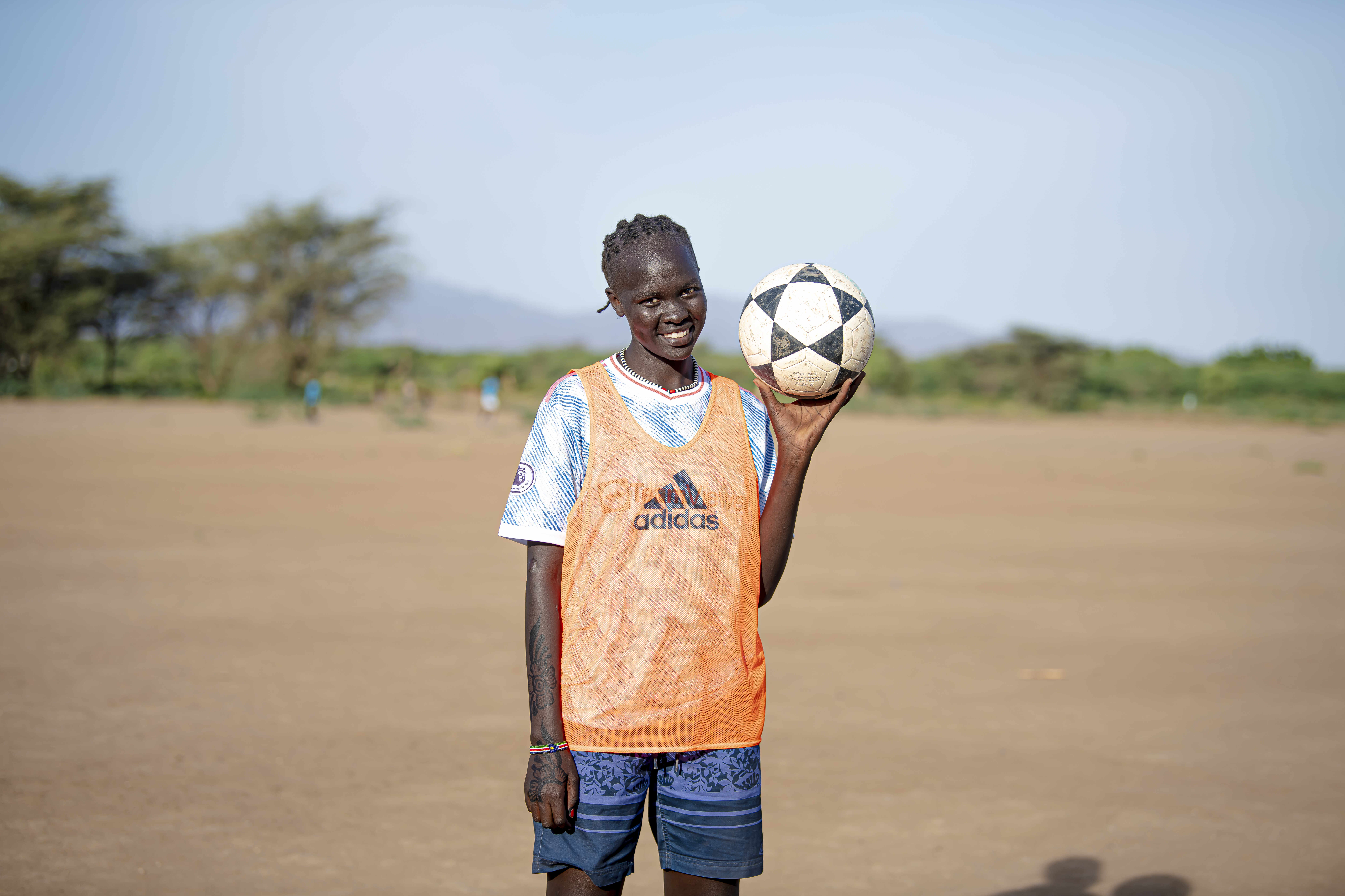 Refugee girl holding a football and smiling at the camera