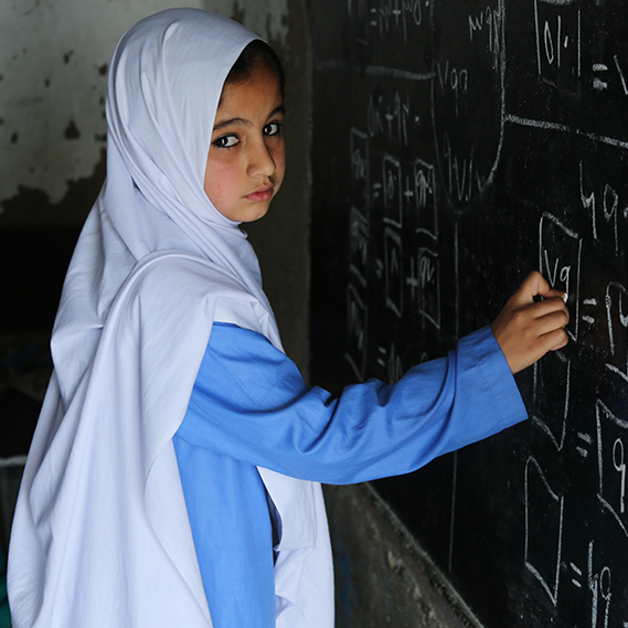 9 year old Mariam draws on a chalkboard at the UNHCR funded primary school for girls in Peshawar, Pakistan.
