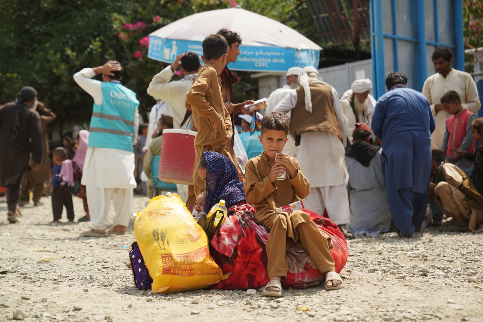 Afghan boy sits on bags at Torkham border crossing as families returning from Pakistan receive assistance from UNHCR. 