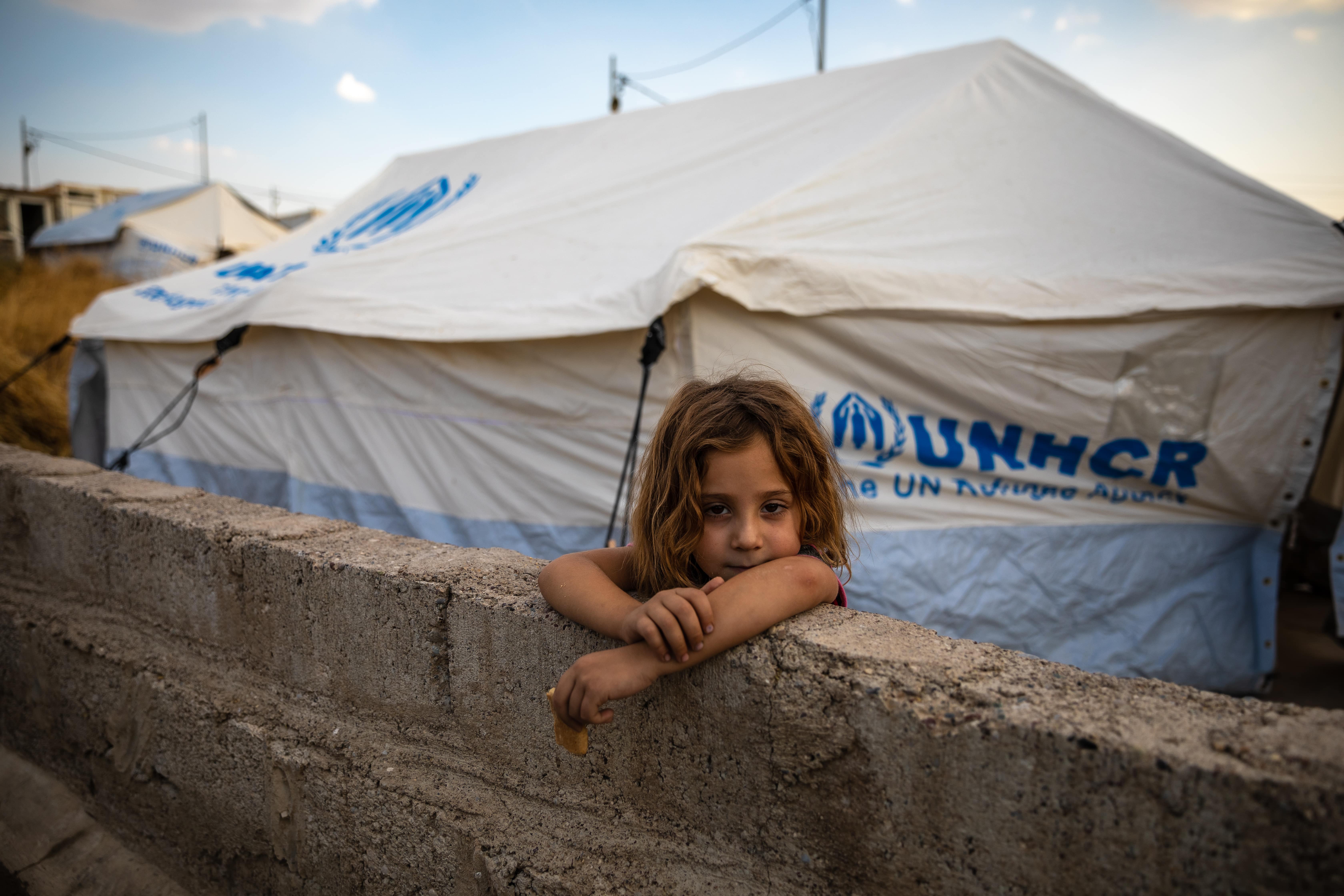 Eight-year-old Raghda Abbas Suleiman looks over a wall near her shelter at Bardarash camp in Duhok, Iraq, a day after arriving with her family.