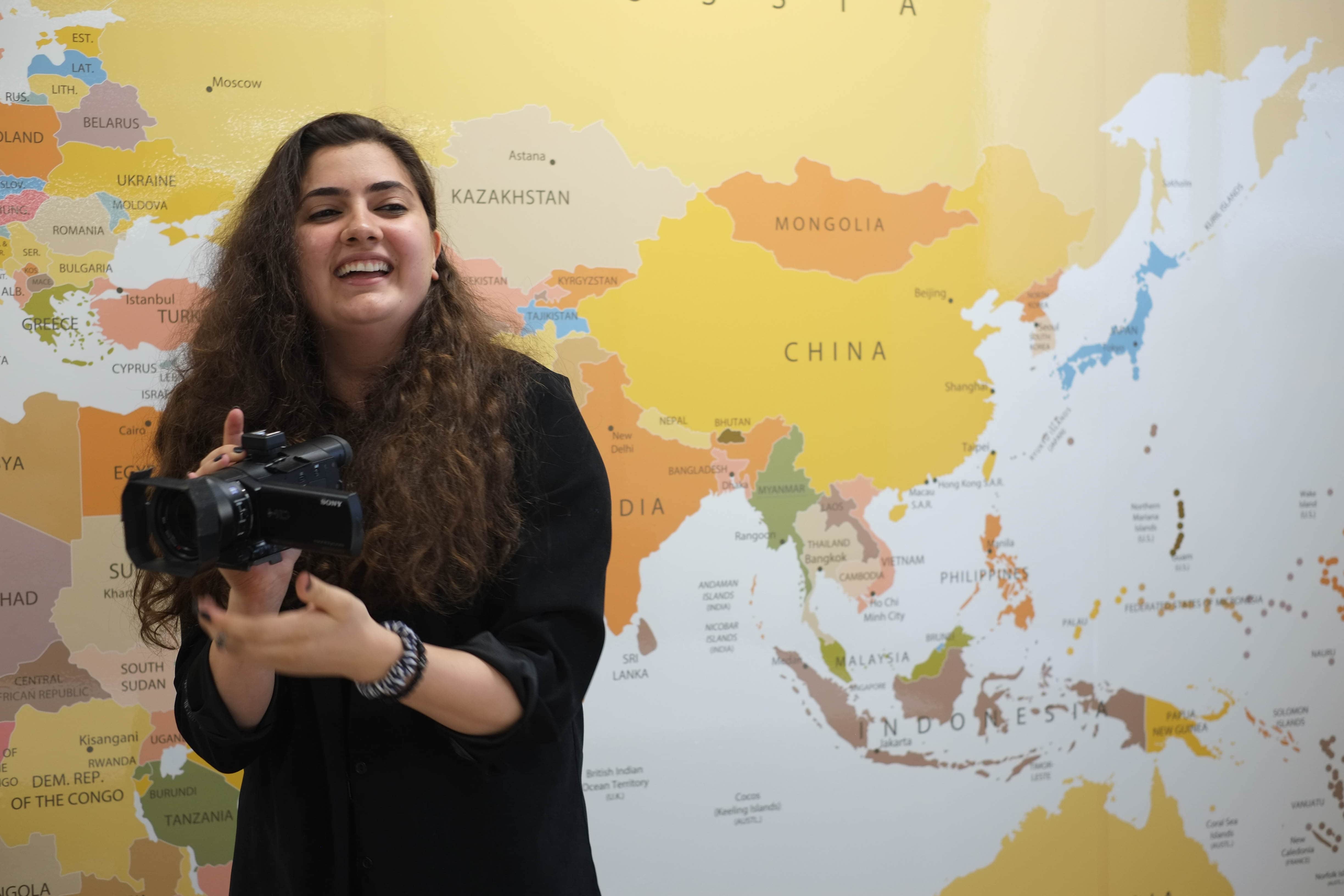 Winner of 2022 Australia for UNHCR Beddie Scholarship holding camera.