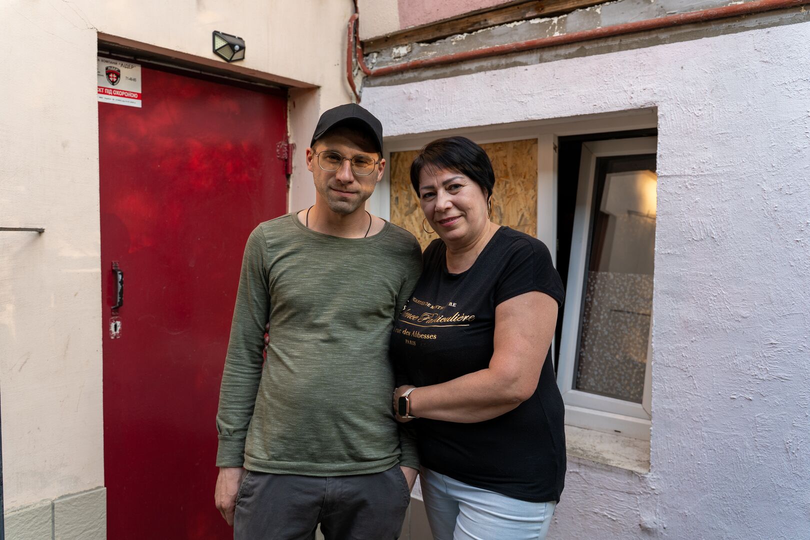 Halyna, 55, and her son Mykola, 32, outside their Mykolaiv home near a school hit by a drone in 2025.
