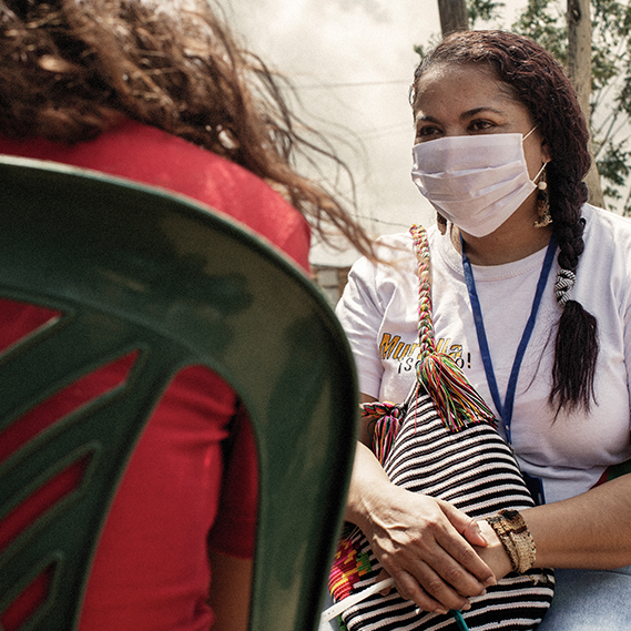 Masked UNHCR worker sits and chats 