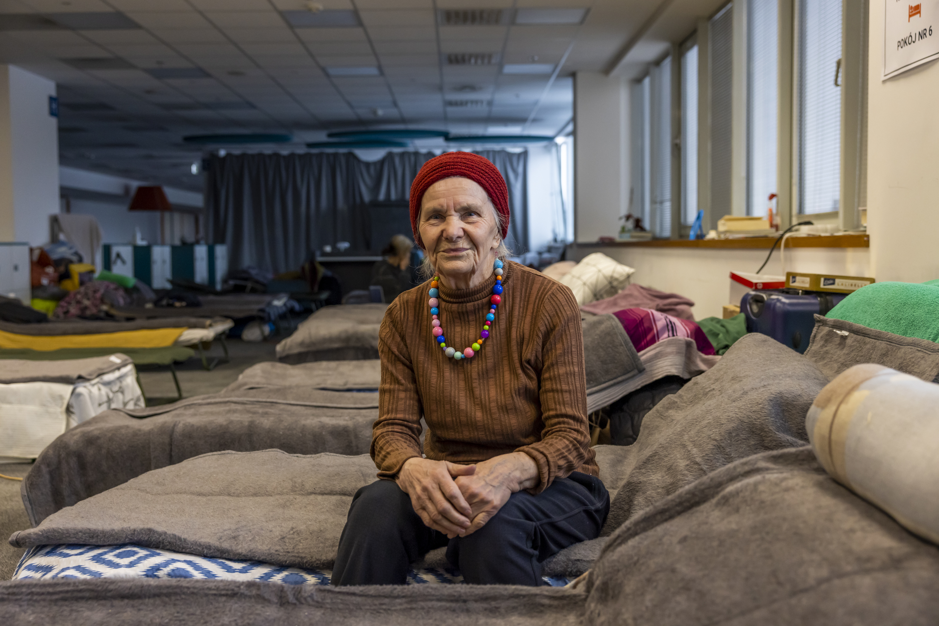 Valentina (83) is sitting on her bed posing at a collective centre in Kraków. 