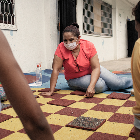 Masked woman sits on the floor laughing 