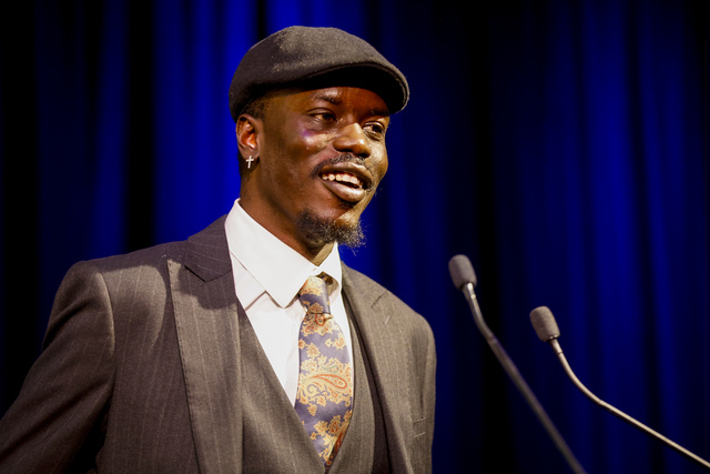 Abraham Kuol stands on a stage and is talking into a microphone