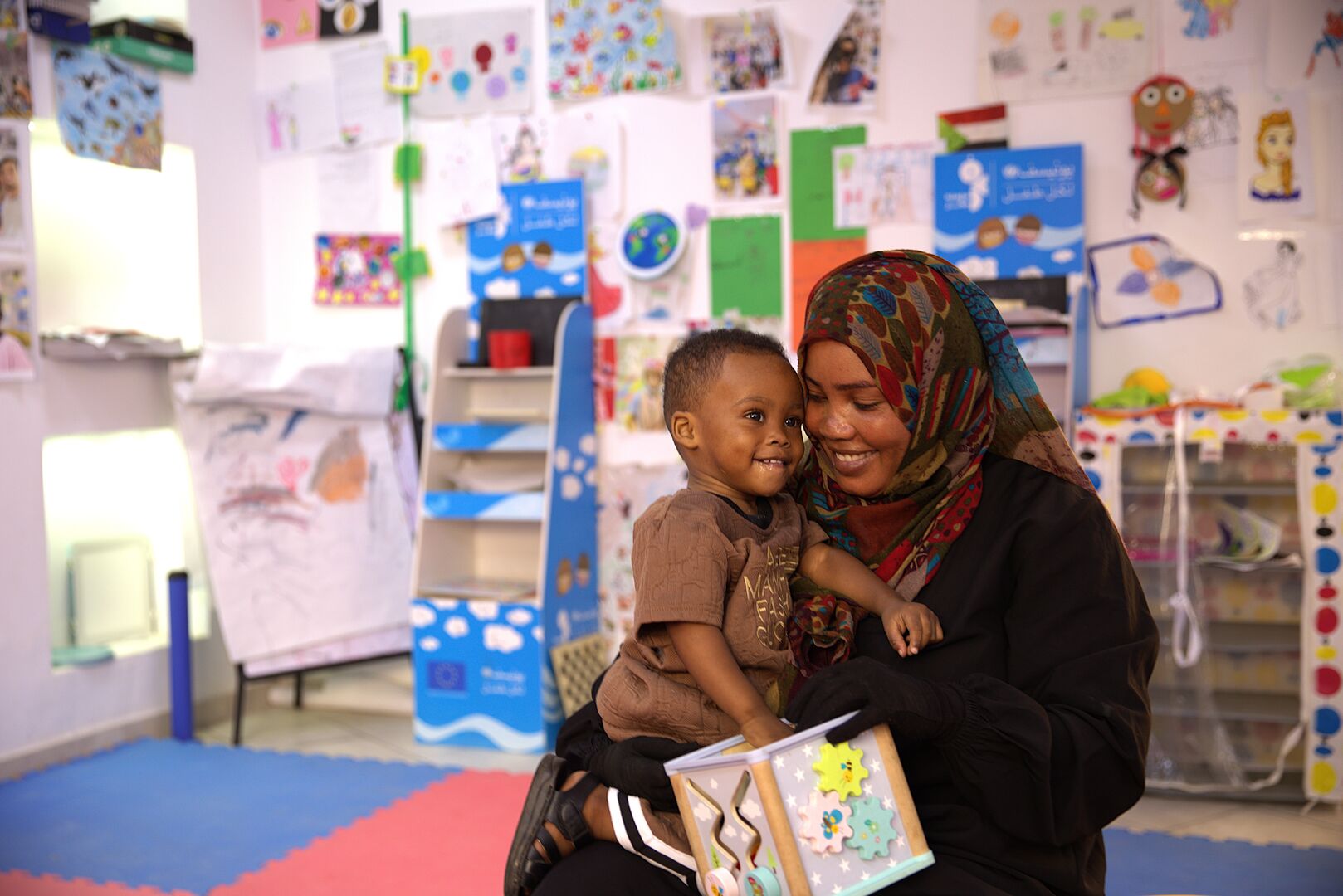 Tahani Hamid, 35, smiling with one of her children, recalling their formerly peaceful life in Sudan’s Darfur region