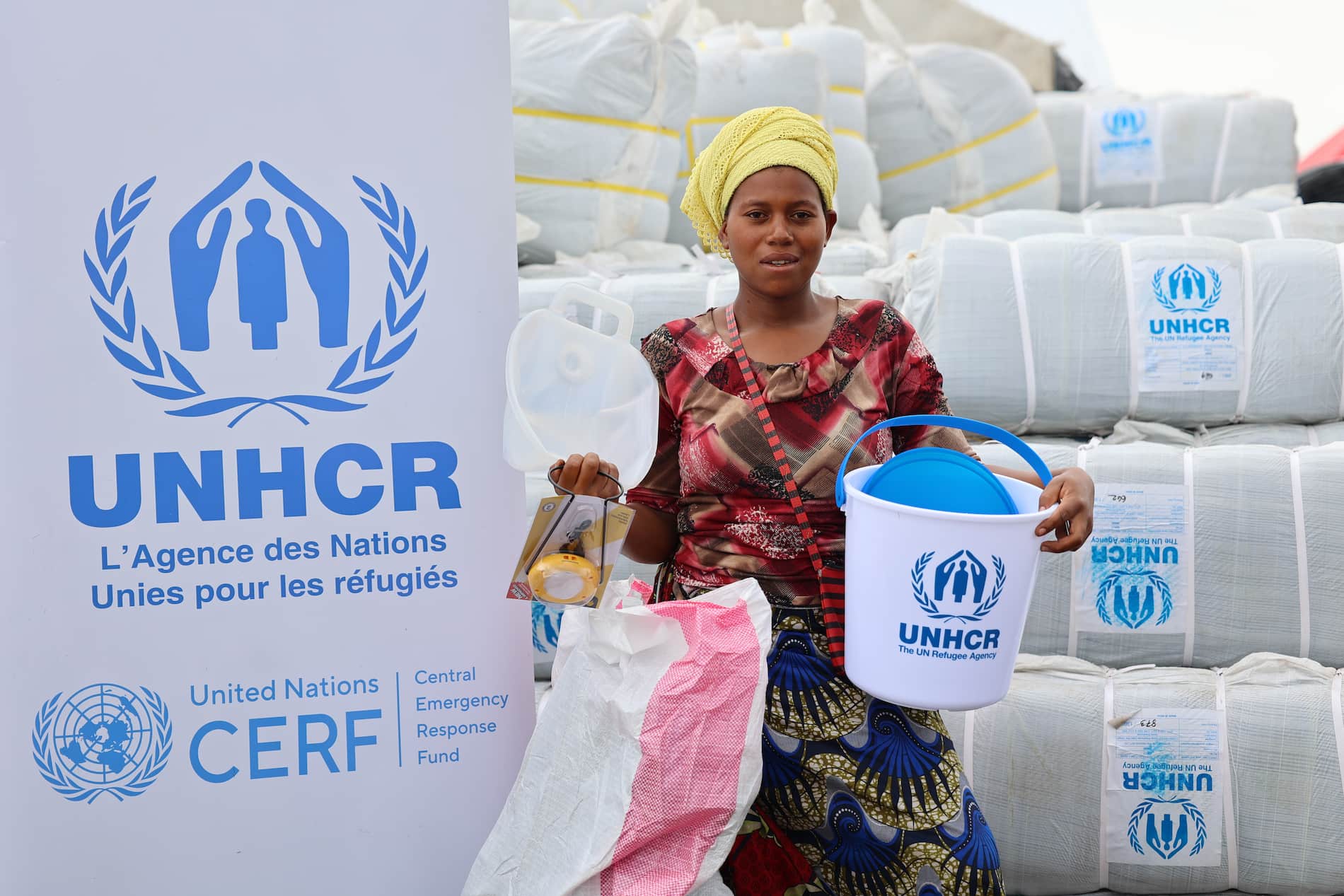 A young woman holding a UNHCR hygiene kit containing soap, toiletries, sanitary towels and solar lamps