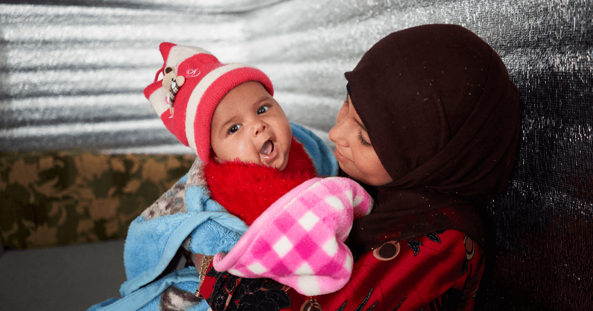 A Syrian mother with her child wrapped in blankets