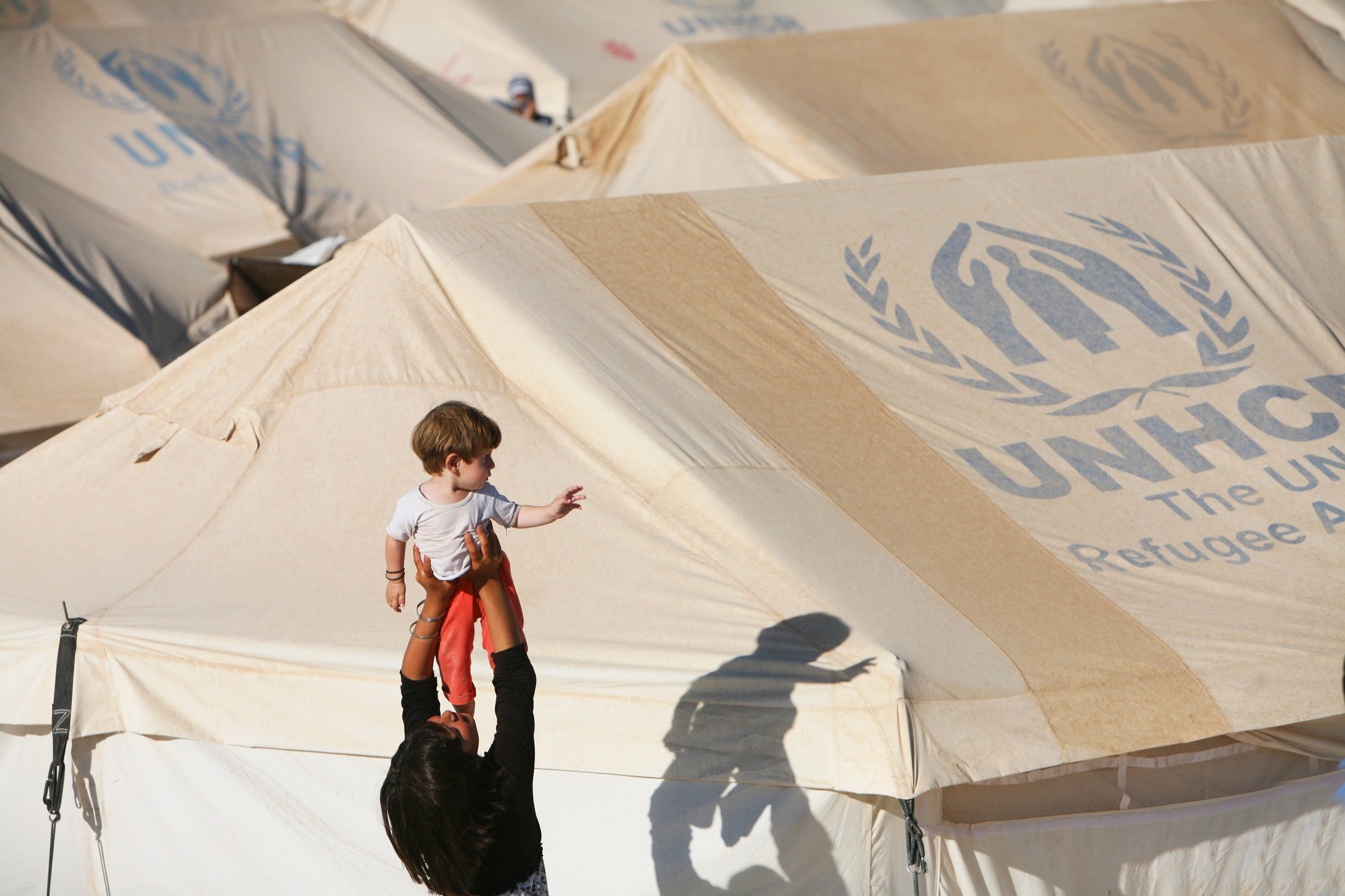 A Syrian girl plays with a young child during the cooler hours of late afternoon in the Akcakale refugee camp in southern Turkey