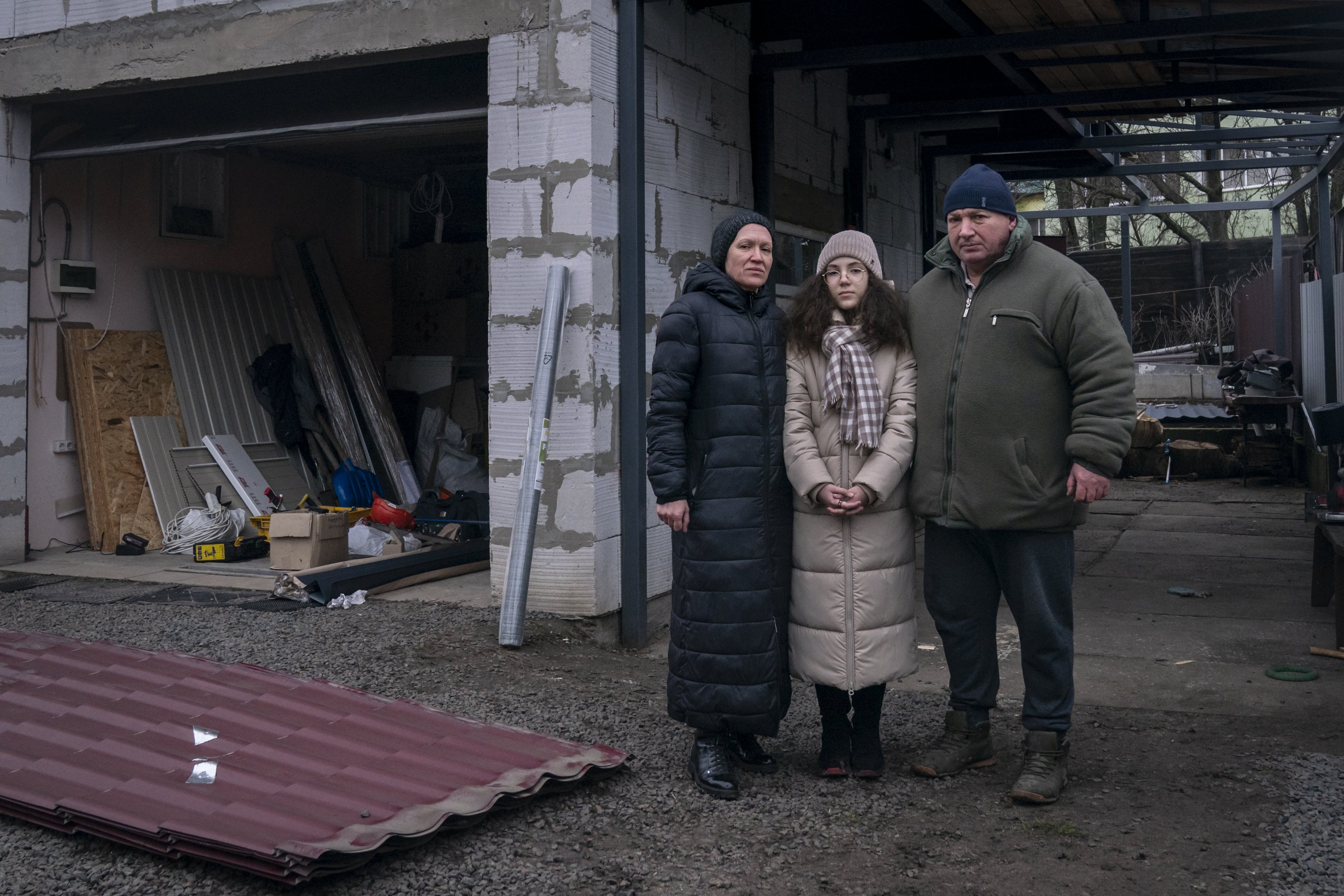 Olena, 50, Andrii, 51, and their daughter, Bohdana, 10, stand in the backyard of their home, in Borodyanka, Kyiv region. 